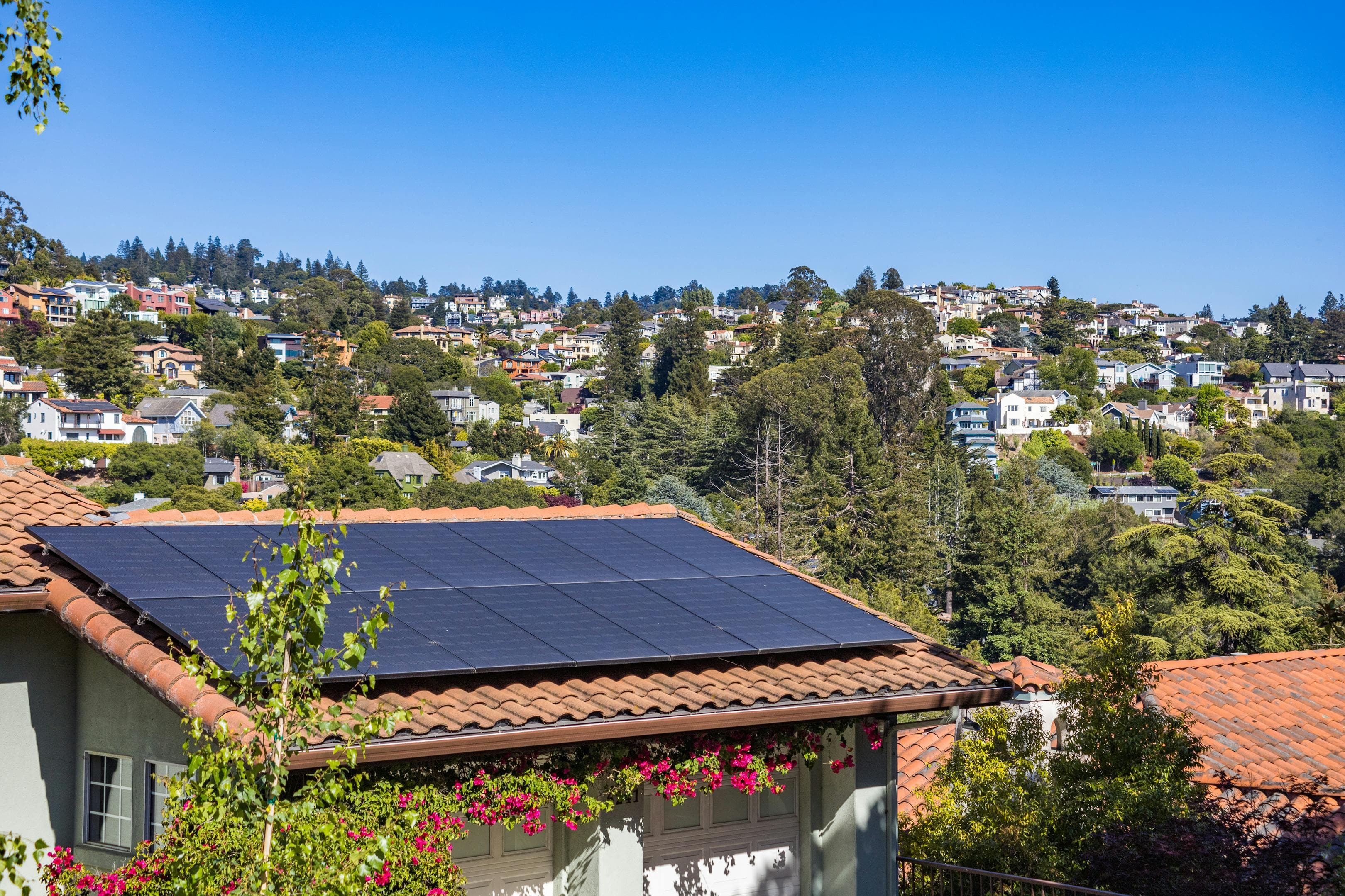 Vorstadthaus mit kompakter Solaranlage auf dem Dach umgeben von Grün unter blauem Himmel